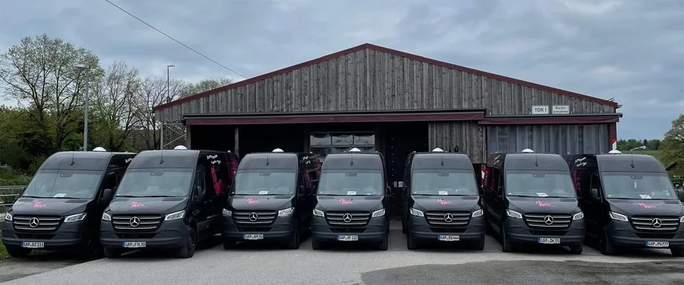 Sieben HiWo-med-Lieferfahrzeuge nebeneinander vor der Lagerhalle in Uffing am Staffelsee.