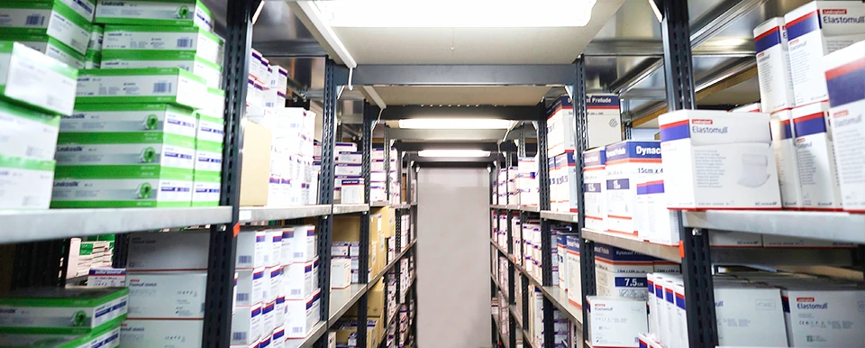 Blick durch einen Gang im HiWo-med-Lager: beidseitig Regale mit Kartons und Verbandmaterial bis unter die Decke.